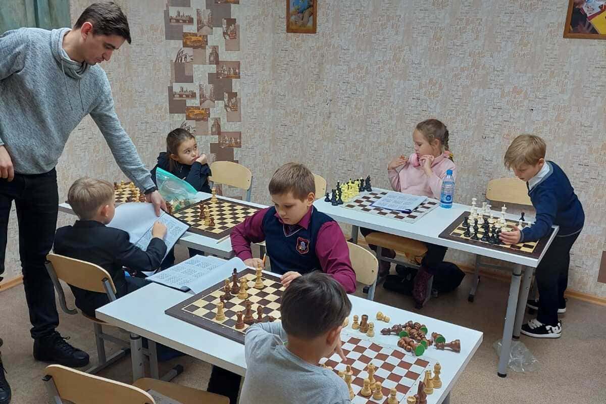 преподаватель по шахматам объясняет детям как играть в шахматы